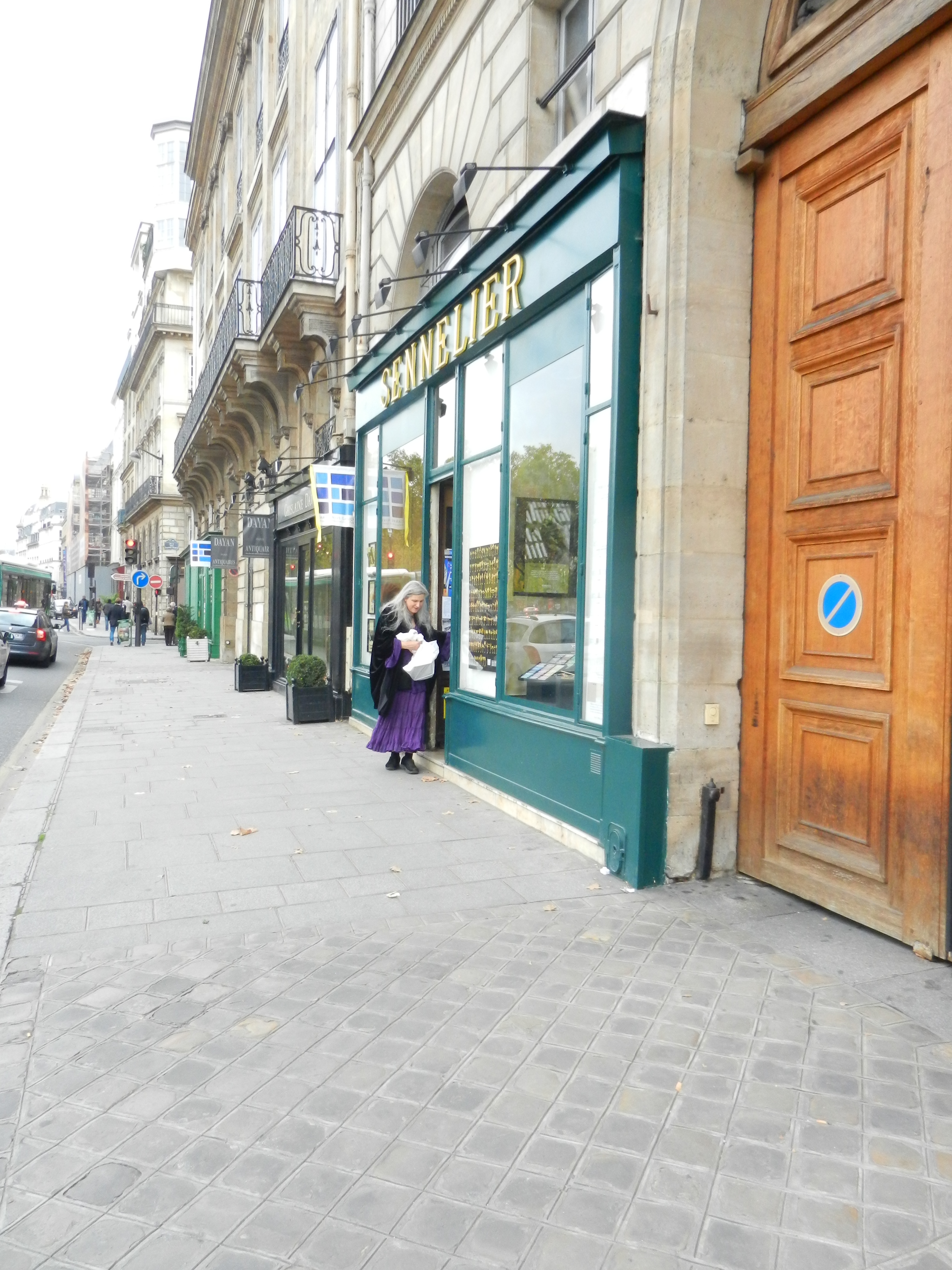 A beautiful, historic art supply store storefront with elegant green-and-gold signage on a charming city street.