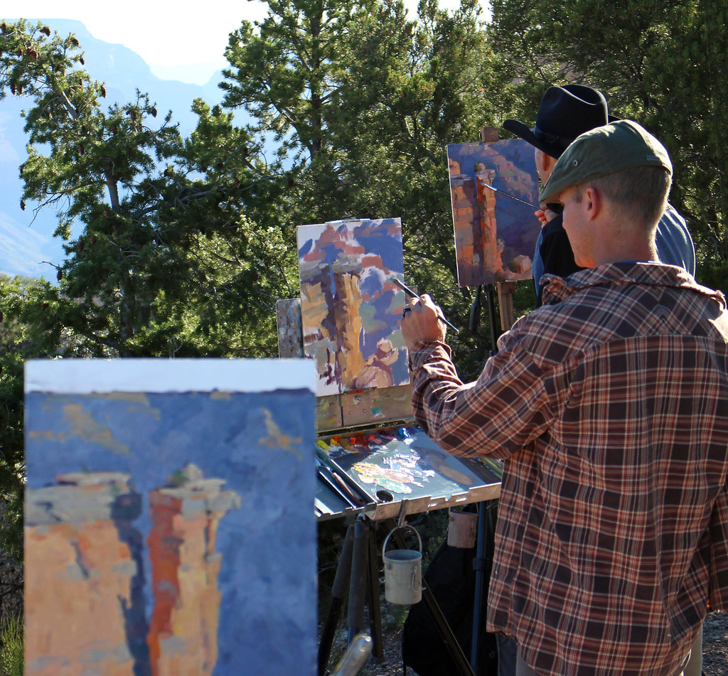 Fellow watercolour artists painting outdoors together en plein air, easels set up facing a scenic natural landscape.