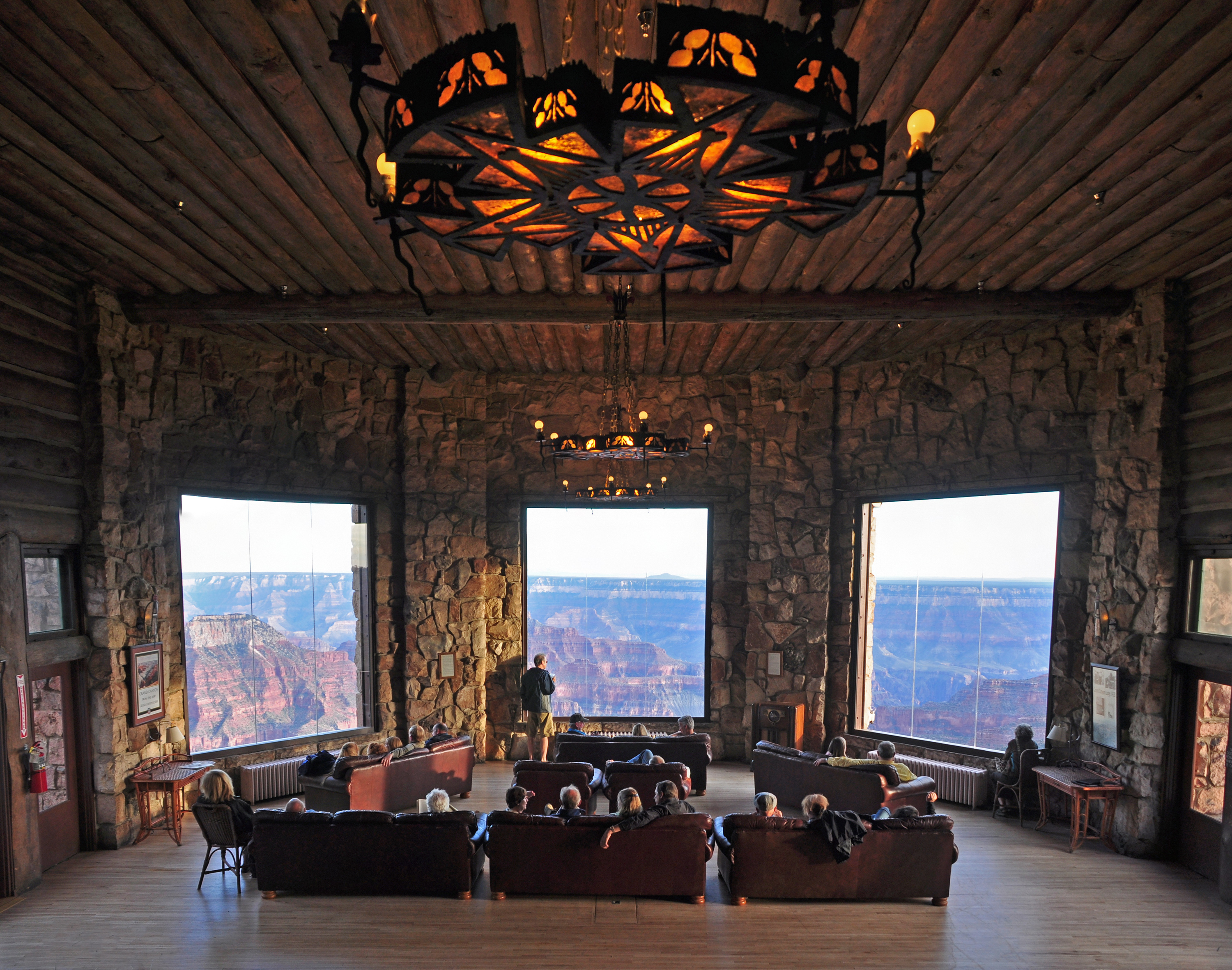 A grand indoor venue with large windows framing a beautiful, sweeping natural scenery view, filled with comfortable seating for guests.